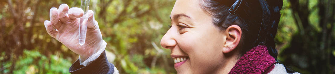 Woman holding test tube and smiling.